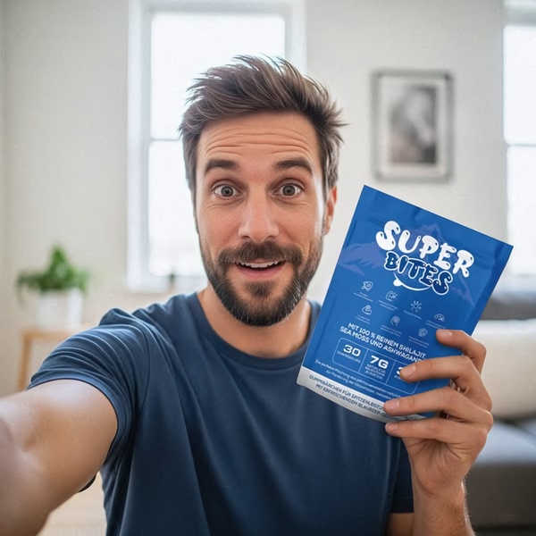 A close-up, selfie-style shot of a male consumer holding a branded pack of Shilajit and Ashwagandha gummies in a bright, casual living space.